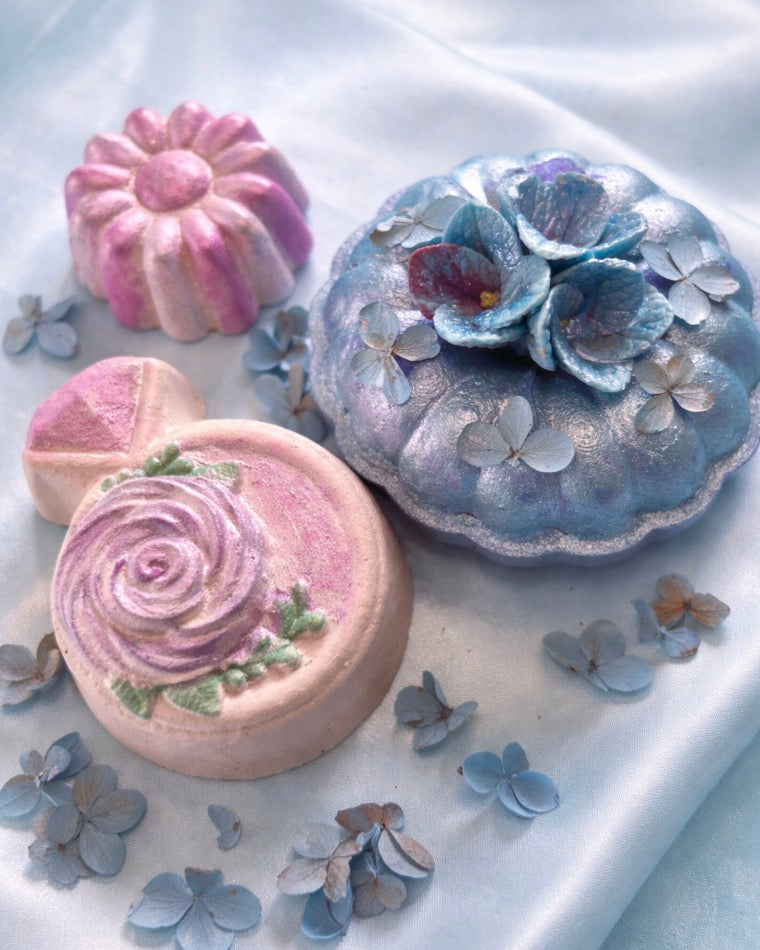 Handmade floral bath bombs in pastel  pink and blue from a luxury spa gift box arranged on a soft romantic background