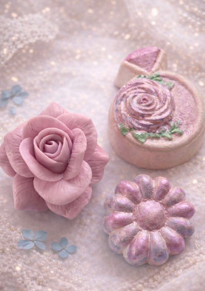 Handmade rose soap and decorative bath bombs from a luxury spa gift box arranged on a soft pastel bacckground.