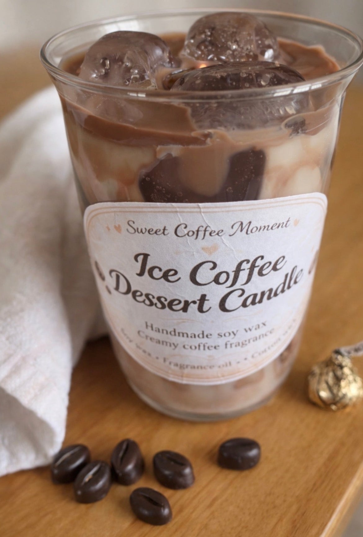 Ice coffee dessert candle with coffee beans and a label on a wooden surface