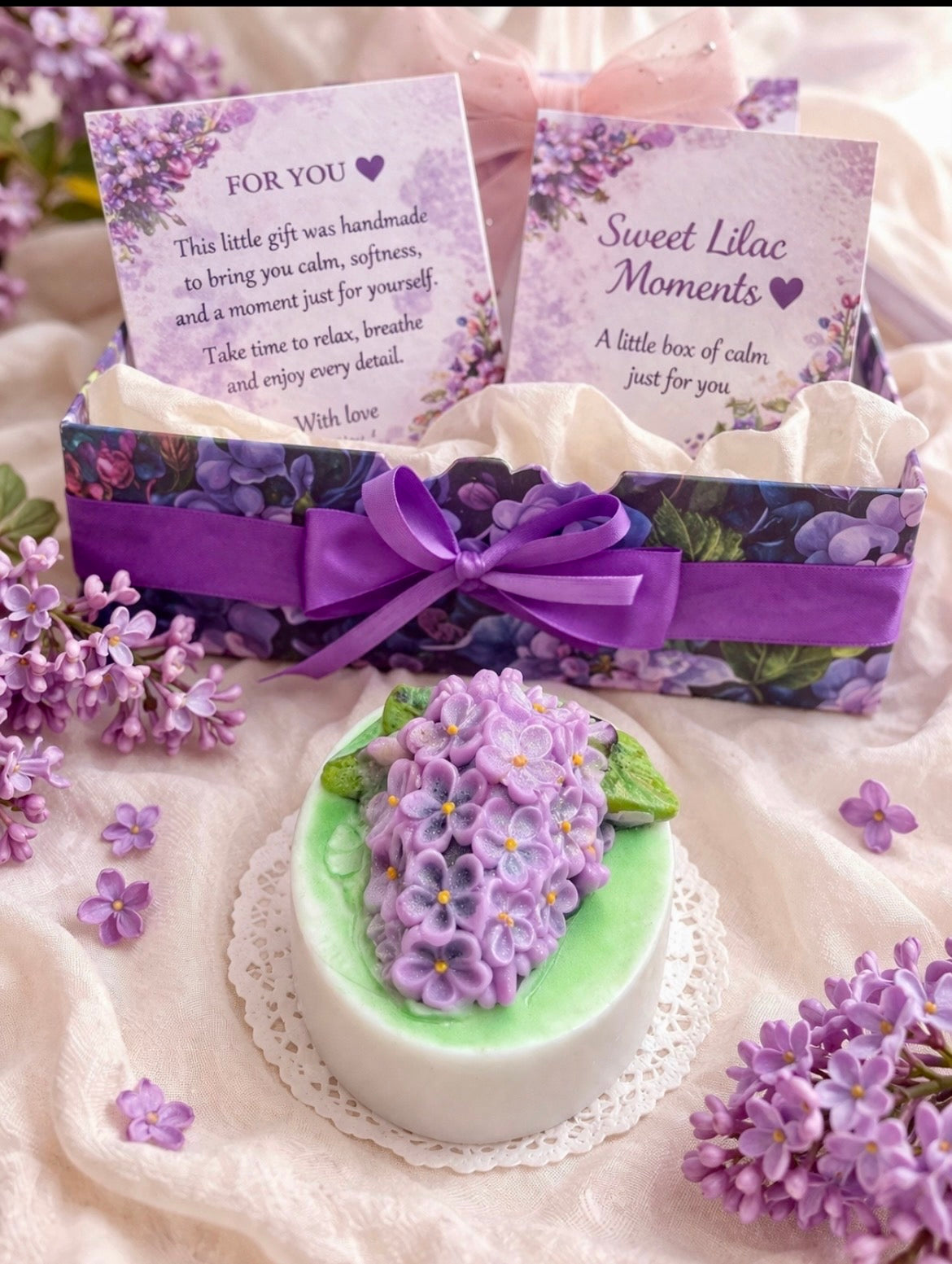 Lilac Spa Gift Box with personalised card and handmade lilac flower soap, beautifully wrapped with a purple ribbon and surrounded by fresh lilac blossoms.