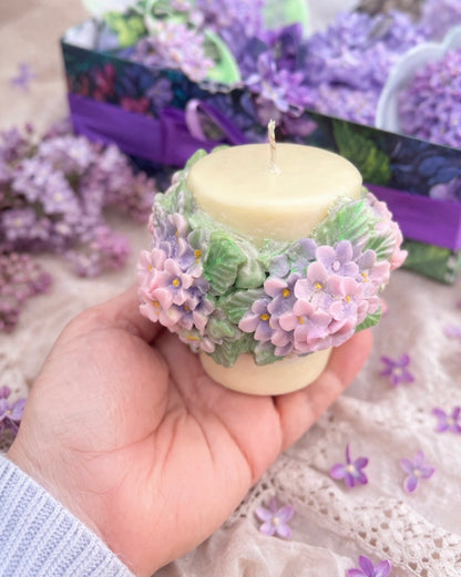 Handmade soy candle decorated with delicate lilac flowers, held in hand to show size, part of the romantic Lilac Spa Gift Box for her.