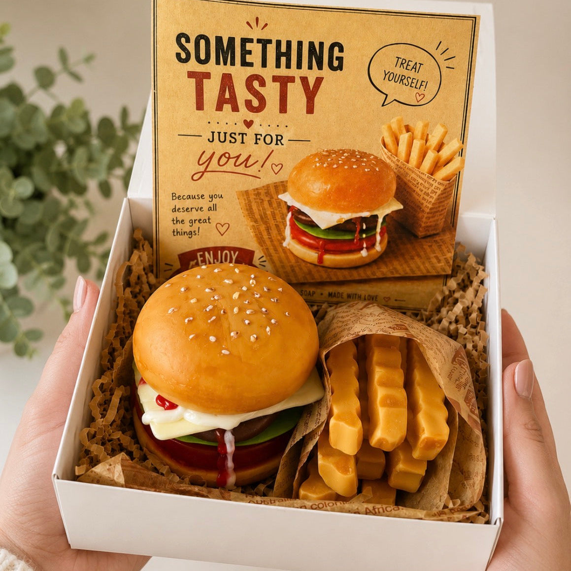 Open gift box featuring a handmade cheeseburger soap, fries soap and greeting card. Realistic food-inspired soap gift ready for gifting.