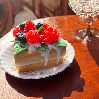 Handmade realistic double square waffle soap cake with berries and green leaves, with creamy drip details an on a white plate on a wooden table 