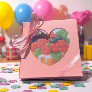 Pink gift box with a heart-shaped window displaying berries on a colorful confetti background